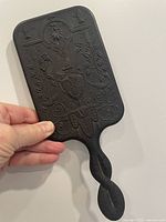 Back side showing detailed embossed decorative pattern and twisted handle of the gutta percha hand mirror.