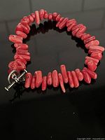 Full bracelet laid flat showing red coral stones and metal toggle clasp