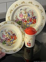 Plate, bowl and sippy cup shown together with Bunnykins themed design on cream background and gold bunnies around rim.