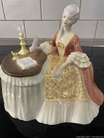 Front and side view showing detailed face, dress, and writing desk with candleholders and book.