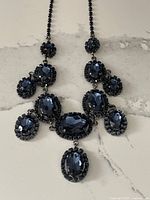 Full view of sapphire blue lavaliere necklace with multiple claw set stones laid flat showing design and chain.