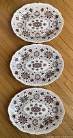 Three oval Masons Ironstone platters with brown Bow Bell floral pattern, laid out on wooden floor, showing identical sizes.