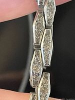 Close-up of the hexagonal links with clear paste stones in a channel setting, connected by metal joints.