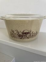 Side view of the Pyrex 1 quart casserole dish showing the Forest Fancies mushroom pattern on almond speckled background.