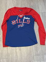 Front view of Buffalo Bills women's long sleeve shirt with red mesh sleeves, blue torso, logo and lace neckline detail.