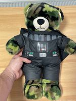 Front view of the toy showing camouflage teddy bear with Darth Vader costume with printed chest panel detail.