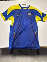 Full view of Ecuador jersey showing front design, blue base with yellow on shoulders and sleeves.