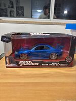 Front view of blue Nissan Skyline GTR diecast model in original box with damaged corner.