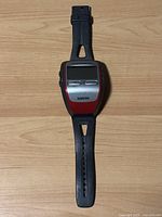 Top view of Garmin Forerunner 305 watch showing black rubber strap and rectangular screen with red and silver casing.