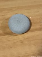Top view of Google Nest Mini smart speaker showing light gray fabric mesh surface.
