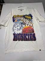 Front view of a white long-sleeve shirt with large colored print celebrating the 1999 National Championships of UConn Huskies basketball.
