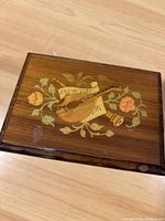 Top of wooden music box showing floral and mandolin musical instrument inlay.