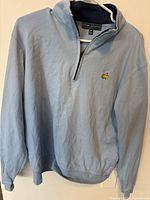 Front view of light blue Masters Collection quarter-zip pullover showing embroidered logo and zipper.