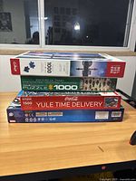 Stack of 4 puzzle boxes including History of Tanks, Earthgraphics, Coca-Cola Yule Time Delivery, and Avengers Marvel. Displayed from side and front views showing box artwork and piece counts.