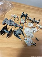 Multiple Star Wars Hot Wheels toy vehicles arranged on a wooden surface including Millennium Falcon, TIE Fighters, X-Wings, and others.