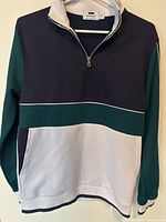 Front view of the Topman quarter zip sweater showing color-block design with navy blue, green, and grey sections, kangaroo pocket, and zipper.