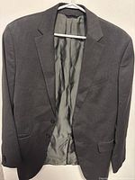 Gray vintage Banana Republic jacket hanging on a hanger with grey satin lining inside visible.