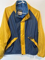Front view of the vintage Banff women's windbreaker jacket, showing navy and yellow color scheme, snap-button collar, and pockets with logo patch.
