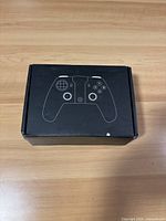 Box with drawing of controller on the top in black packaging.