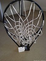 Close-up photo of black basketball rim with white mesh net showing mountable bracket and rim condition.