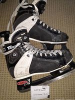 Pair of CCM Tacks hockey skates in black and white with Reebok Pump feature on tongue, displayed side view showing wear and dirt.