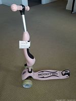 Front and side perspective of the children's pink scooter showing handlebar, deck, and wheels