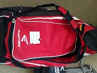 Red and black Easton baseball equipment bag with visible Rawlings branding on included items inside the bag.