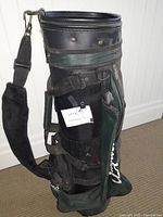 Full view of golf bag showing black and green color scheme, shoulder strap, and wear marks