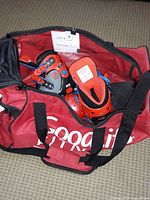 Red Good Life Fitness duffle bag partially open showing Avengers themed children's roller skates, red spiked ball, and wrist guards inside