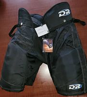 Front view of the HP15 Senior hockey pants showing DR Sports logo and protective padding on thighs.