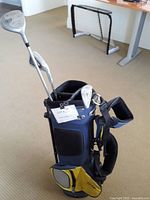 Photo of kids blue and yellow golf bag with three golf clubs including driver and iron