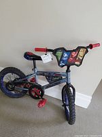 Full side view of Marvel Avengers themed kids' bicycle with visible wear, red pedals, and black tires.
