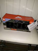 Box of three Ozark Trail pop-up lanterns with some wear and brand markings visible on packaging.