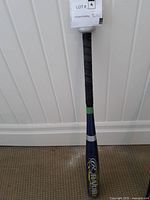 Full view of the Rawlings Razor baseball bat standing against a wall, showing branding and grip details.