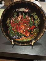 Front of the decorative plate showing colorful, detailed painting of Ruskin and Ludmilla in a medieval setting with castle and forest, ornate gold border