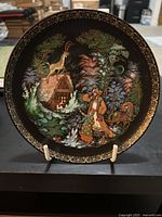 Front of the decorative plate showing the hand-painted Silver Hoof scene with man and woman in forest near cabin under moonlight with gold ornate border.