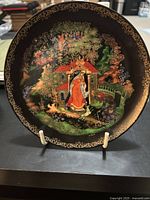 Front view of decorative plate from Russian Legends series depicting Princess and Seven Bogatyrs with detailed colorful illustration and gold accents on black background.