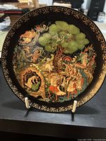 Front view of decorative plate with colorful Russian folk art and gold border