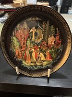 Front view of a decorative plate depicting the Tsar Sultan scene from Russian folk tales with a black background and gold ornate border.