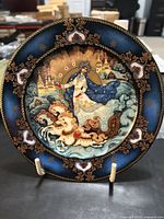 Front of the Russian Seasons plate with artwork of Winter Majesty theme featuring a woman in blue robes on a horse-drawn sleigh in a traditional Russian winter village scene with ornate decorative border.