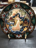 Front of the Russian Seasons plate 2 showing detailed artwork of Springtime Splendor with a woman in traditional dress surrounded by floral and village scenery.