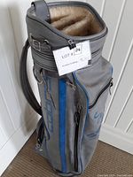 Vintage Cobra golf bag standing on floor showing multiple zipped compartments and strap