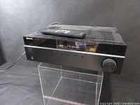 Front view of Sherwood RX-4508 amplifier tuner showing display, selector buttons, large volume knob, and remote control on top.