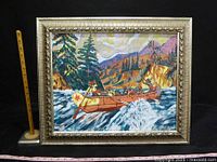 Framed painting showing a river scene with a canoe and mountains, measuring sticks showing size