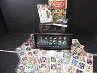Wide view showing the collection of loose baseball cards, framed hockey display, and sports books in the background.