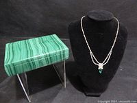 Box and necklace displayed together on black background