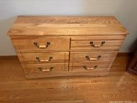 Front view of 6-drawer wooden dresser with leather-style handles on each drawer.