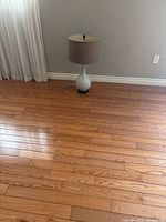 Full view of the retro coffee table lamp placed on wood floor near window with sheer curtains and gray wall.