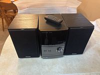 Front and top view of Panasonic portable AM/FM stereo system with two speakers and remote control on top.