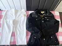 Black Michael Kors jacket with front visible alongside white jeggings on a checkered tablecloth. Jeggings show tags indicating new condition.